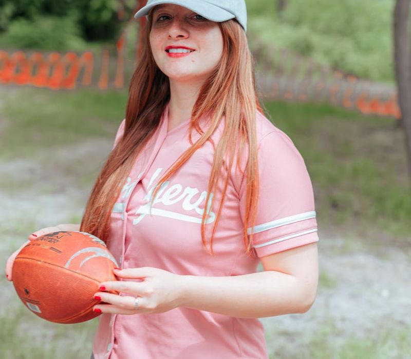 Smiling person performing a light lunge exercise outdoors in a park.